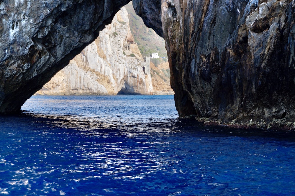 brown rocky mountain beside blue sea during daytime