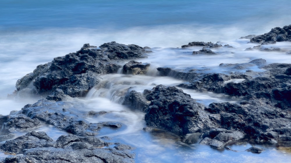 rocky shore with ocean waves under blue sky during daytime