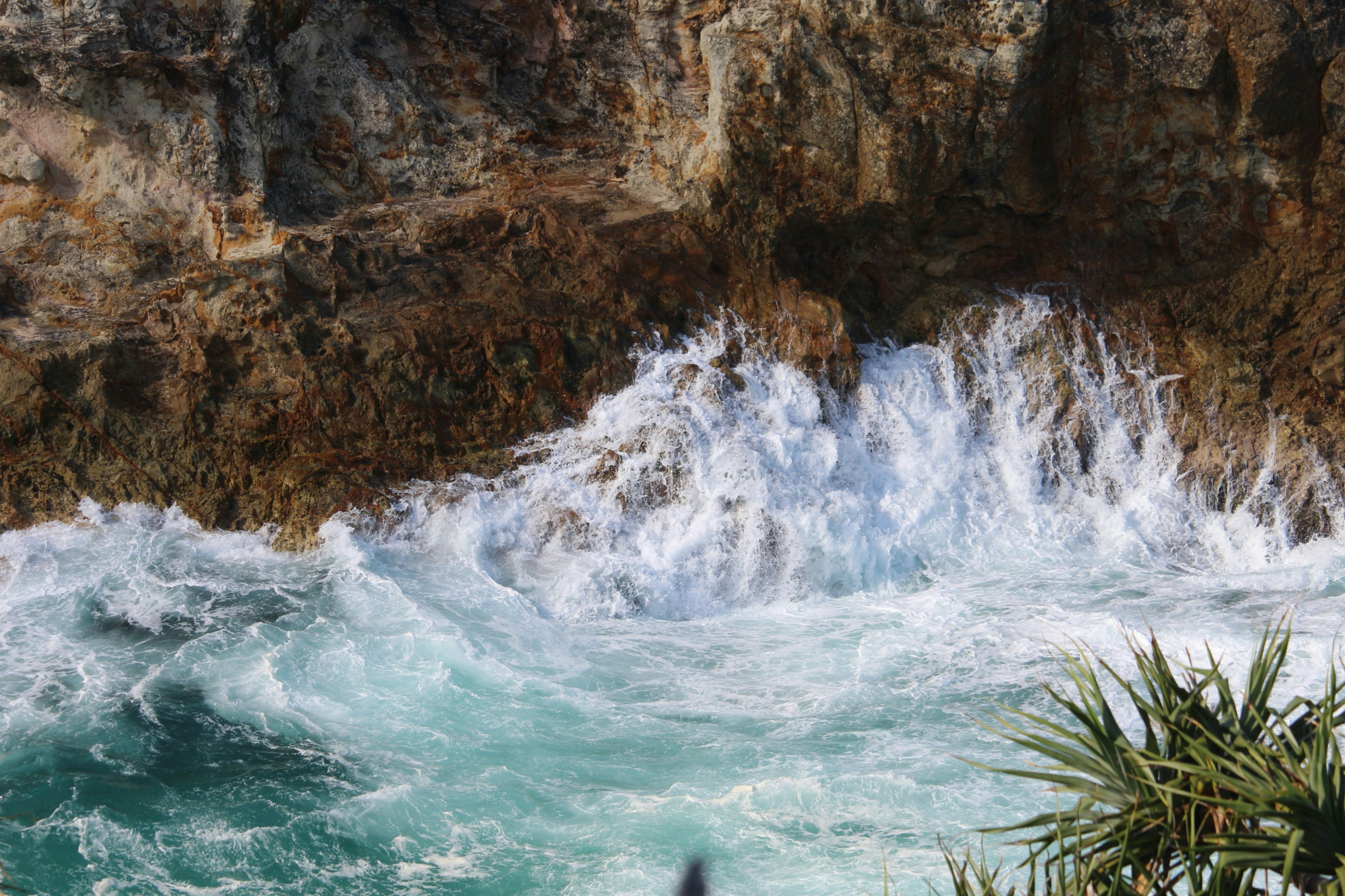 brown rocky mountain beside body of water during daytime, Water flowing off the rocks on North Stradbroke Island