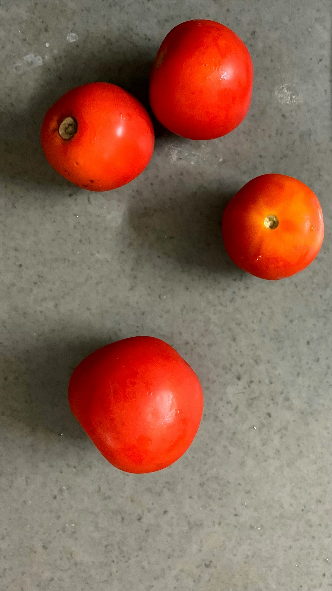 3 red tomatoes on gray surface