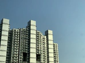 A modern residential building managed by Lopez Meg Properties LLC under a bright blue sky