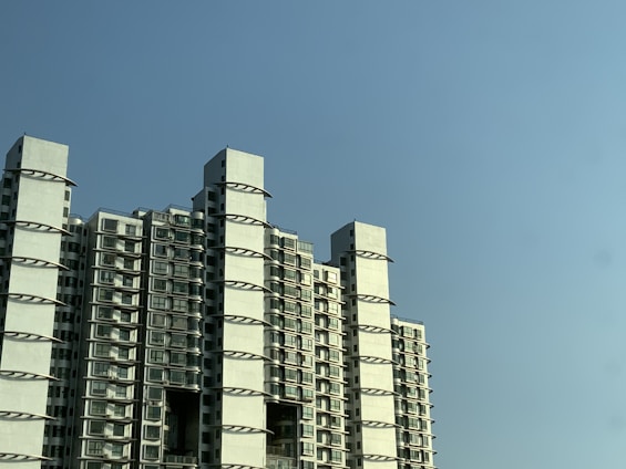 A modern commercial building with retail shops and apartments under a clear blue sky.