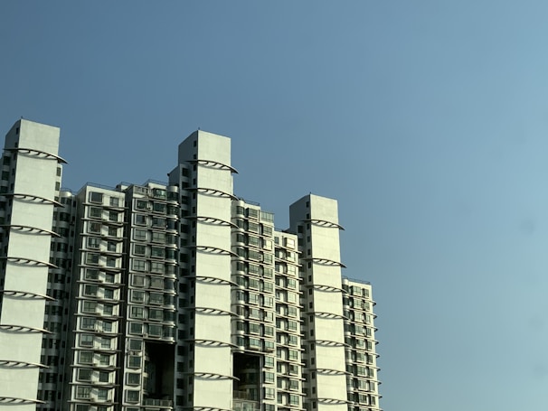 A modern apartment building with large glass windows under a clear blue sky.
