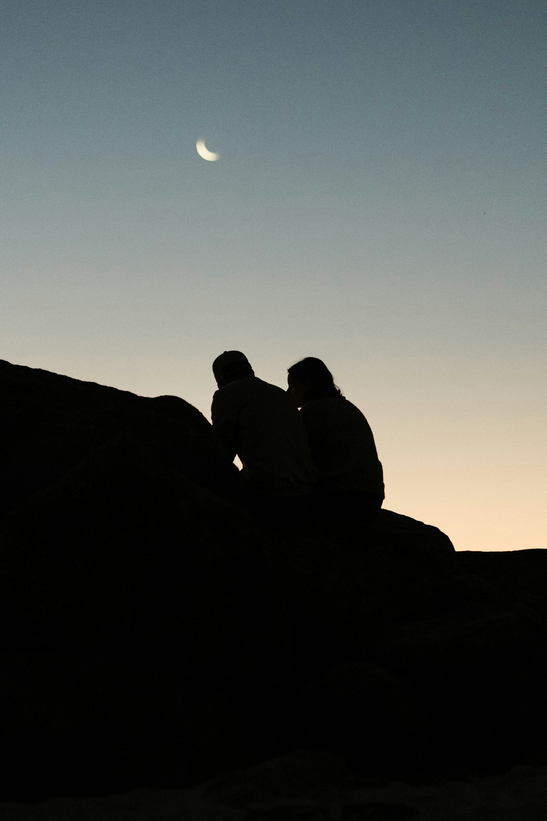 silhouette of 2 person sitting on rock during night time