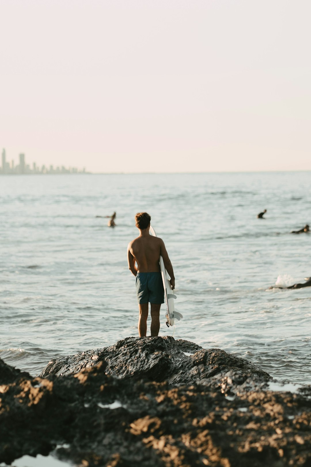 man in black shorts standing on rock near sea during daytime