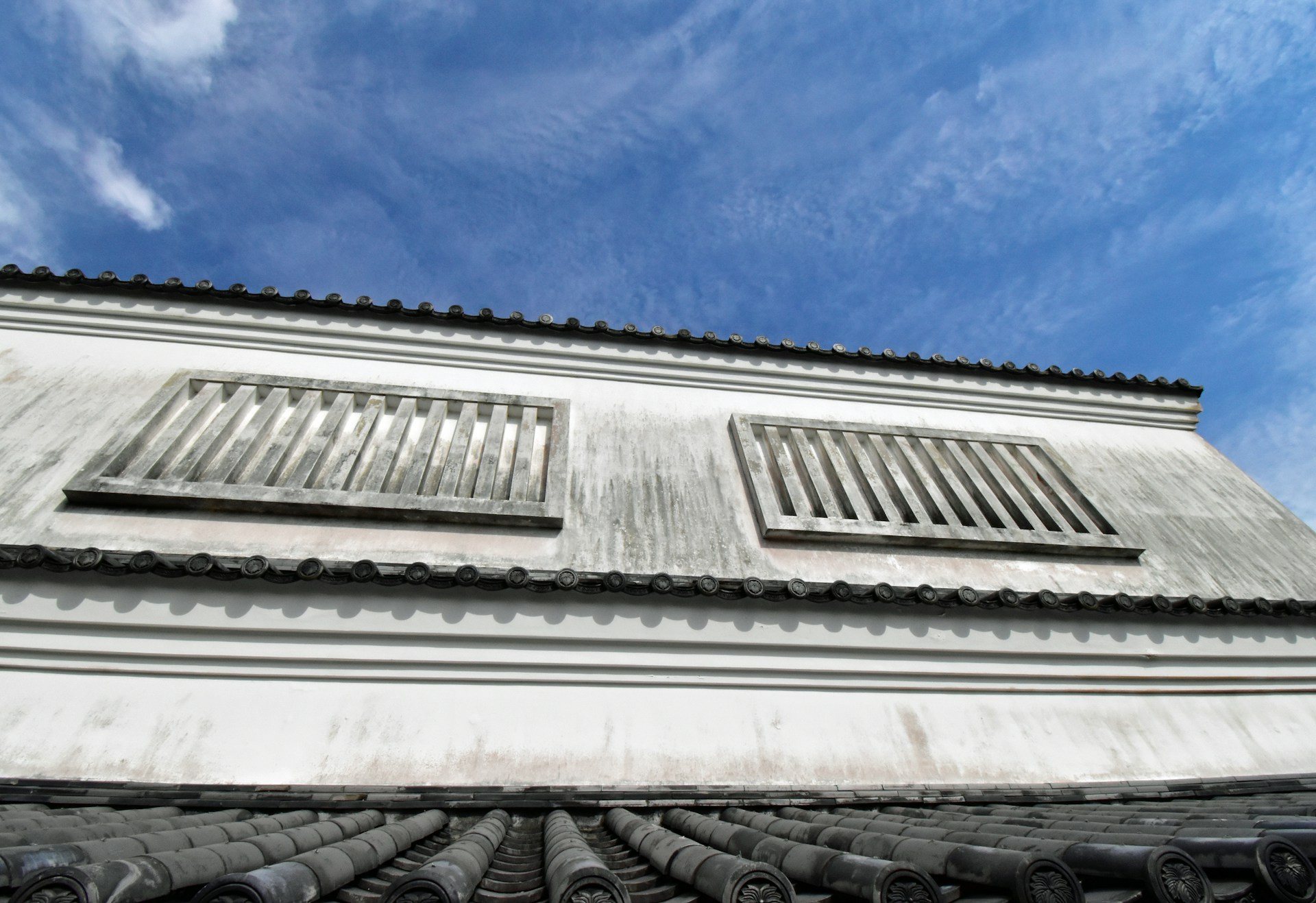 Close-up of a restored building facade with smooth white plaster and subtle blue accents under the clear Mallorcan sky.