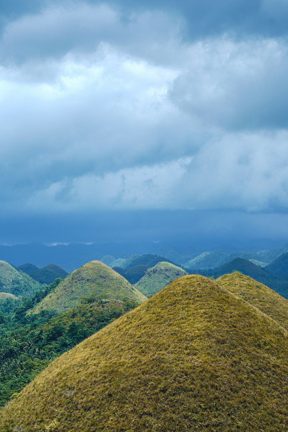 green grass covered mountain under white clouds during daytime