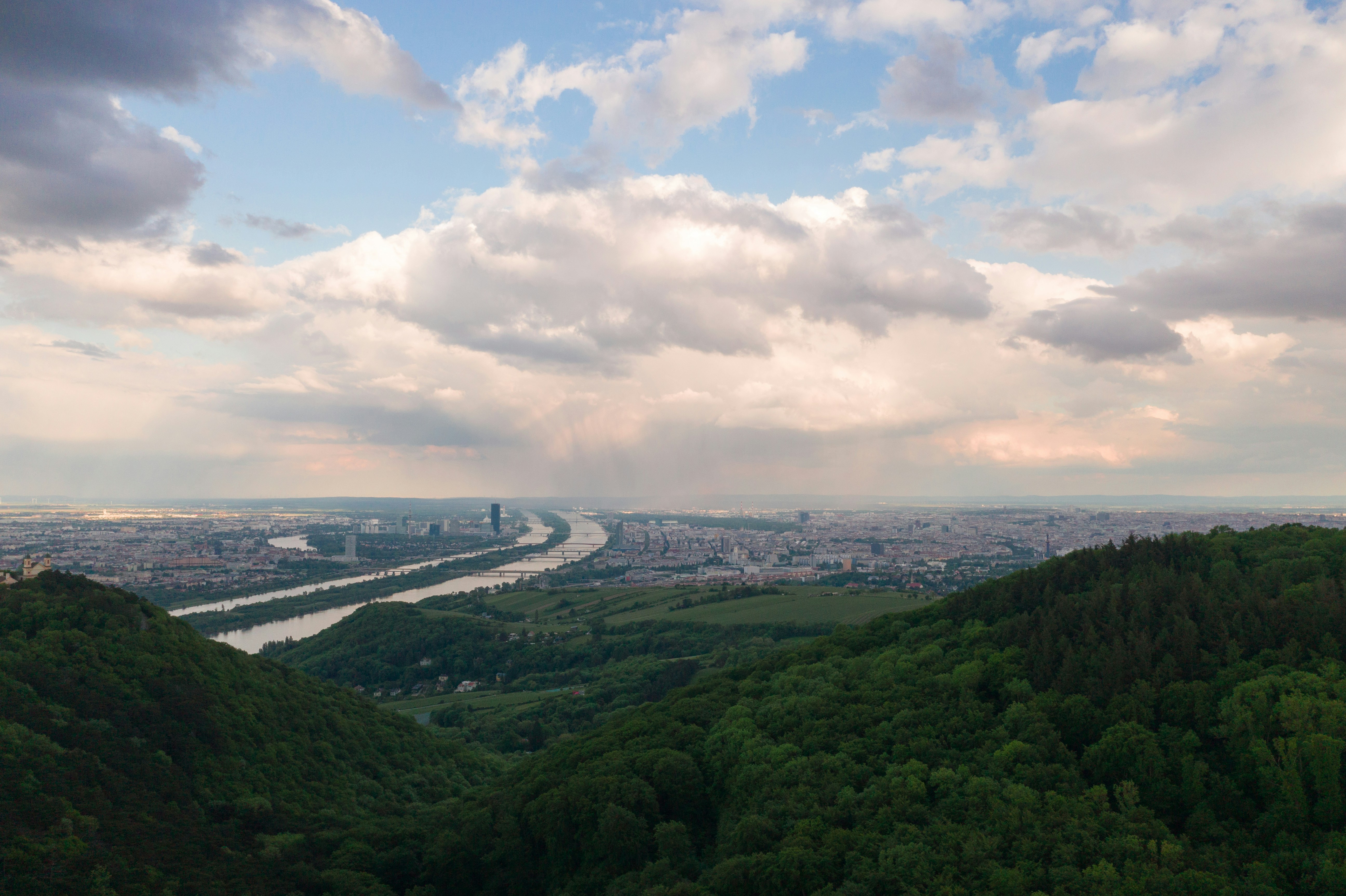 green trees and mountains under white clouds and blue sky during daytime