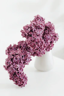 Elegant lilac and white floral arrangement with green leaves in a rustic vase