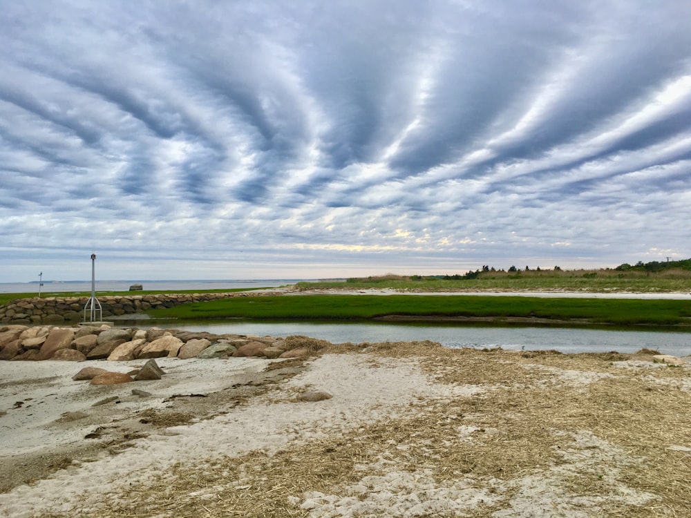 green grass field under blue sky and white clouds during daytime