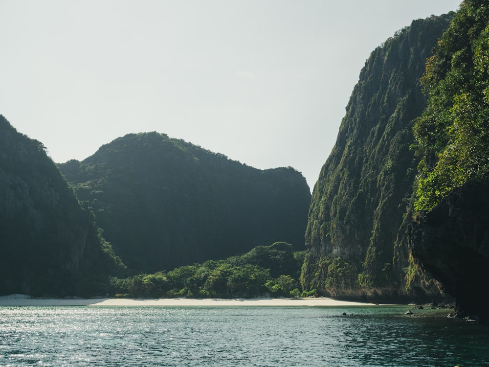 green and black mountain beside body of water during daytime