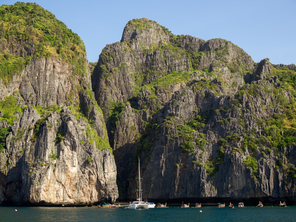 weißes Boot auf See in der Nähe von Brown and Green Rock Mountain tagsüber