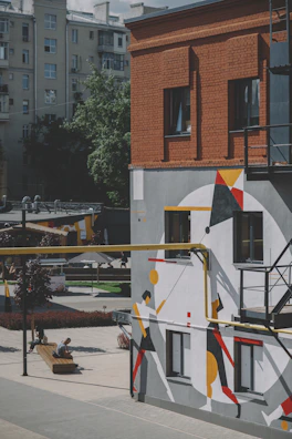 Artist painting a bold, minimalistic mural in an urban setting.