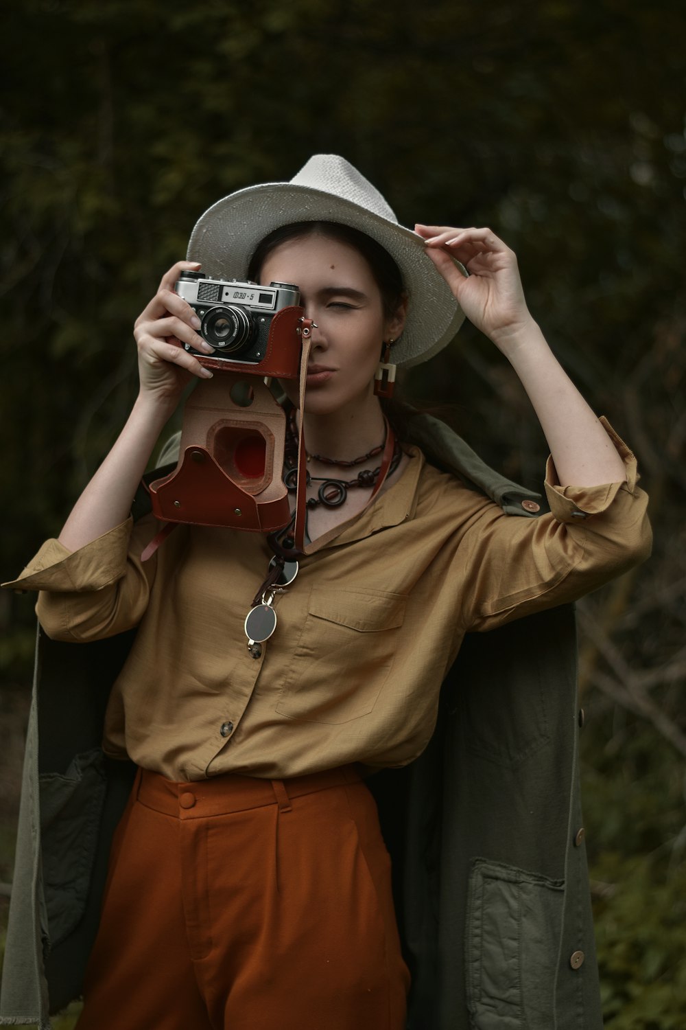 person in brown jacket holding red and silver camera