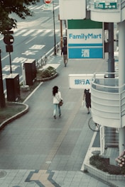 woman in white shirt walking on sidewalk during daytime