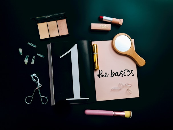 A bright, airy flat lay of skincare and makeup products in soft neutral tones with gold accents.