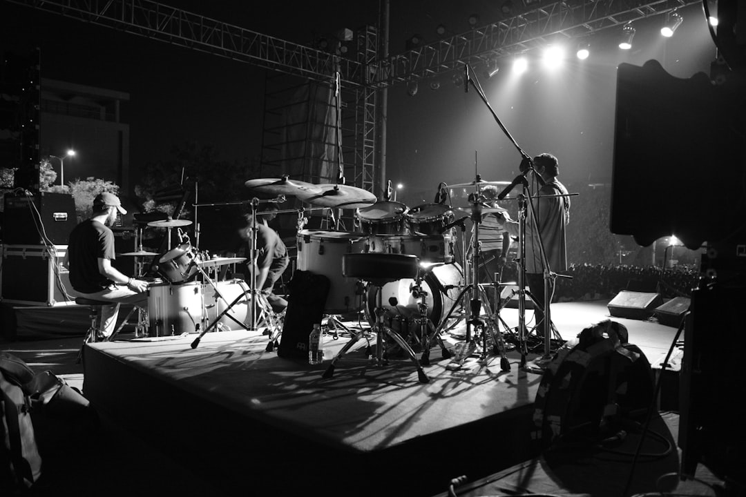 grayscale photo of man playing electric guitar on stage