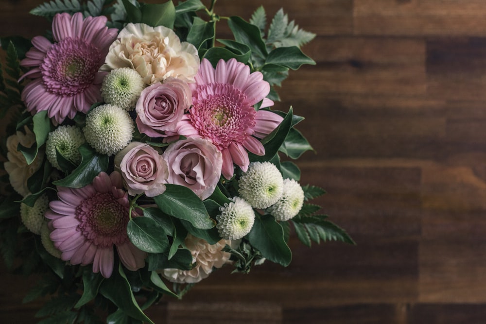 pink and white flowers on brown wooden table