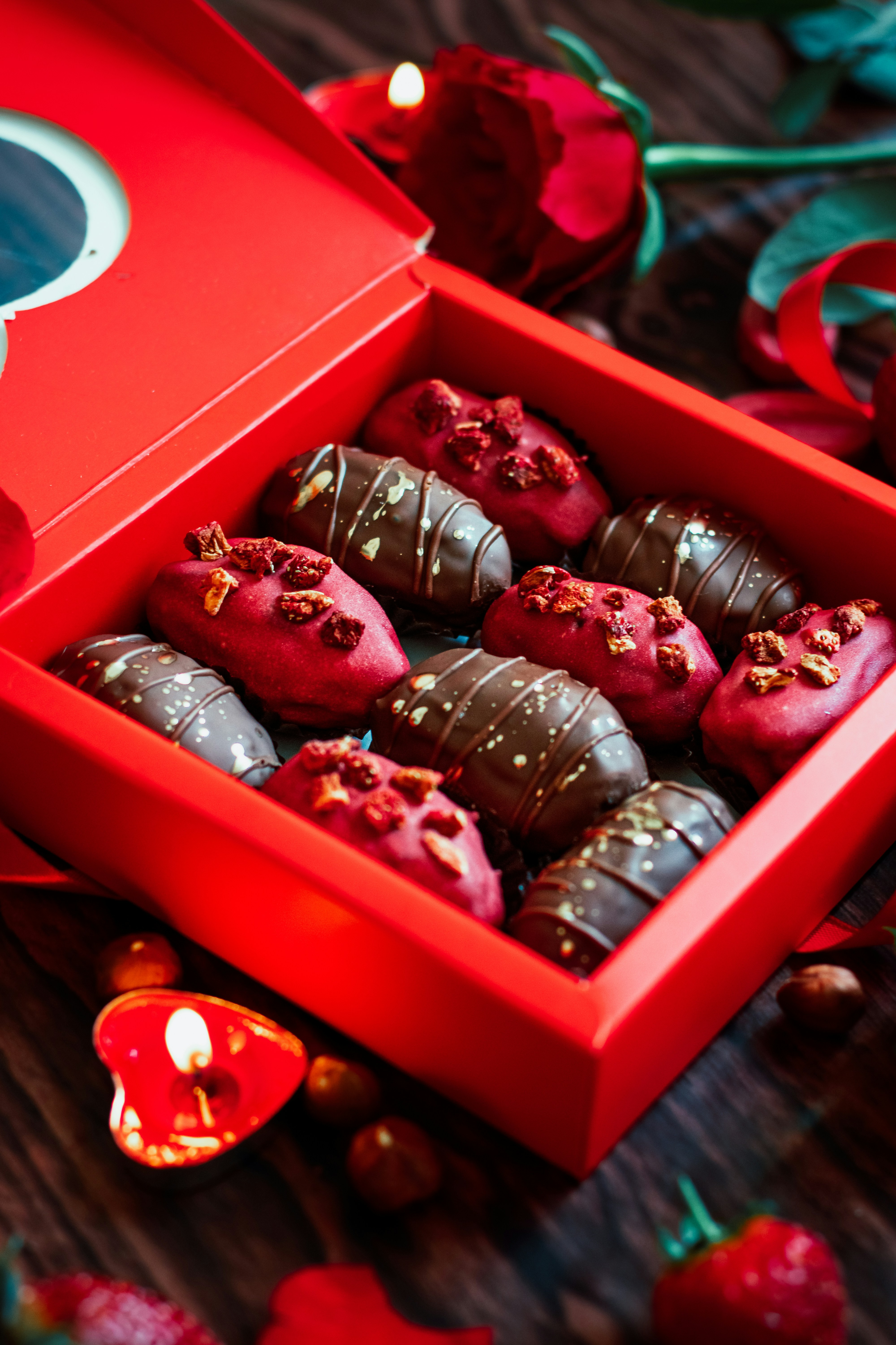 Heart-shaped box of assorted chocolates with red roses on romantic candlelit table