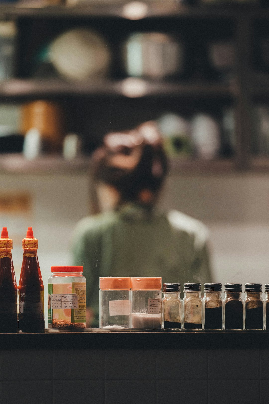 man in green shirt standing near glass bottles