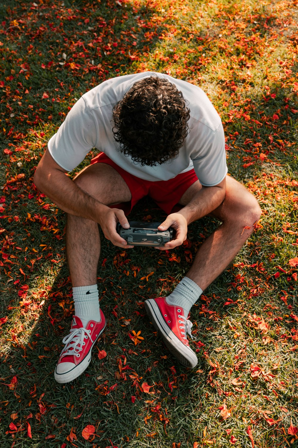 man in white t-shirt and black shorts sitting on ground