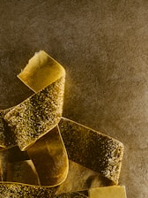 Close-up of a golden ribbon elegantly wrapped around a vibrant red background, highlighting the brand's signature colors.