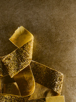 Close-up of shimmering rose gold ribbons twisting softly against a deep burgundy gradient.