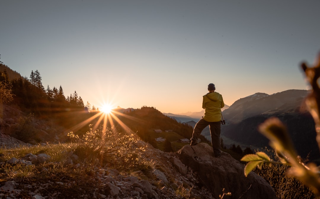 man in yellow jacket standing on rock formation during daytime