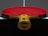 A table tennis paddle with a red rubber surface is placed upright on a dark table, displaying its wooden handle with colorful stripes.