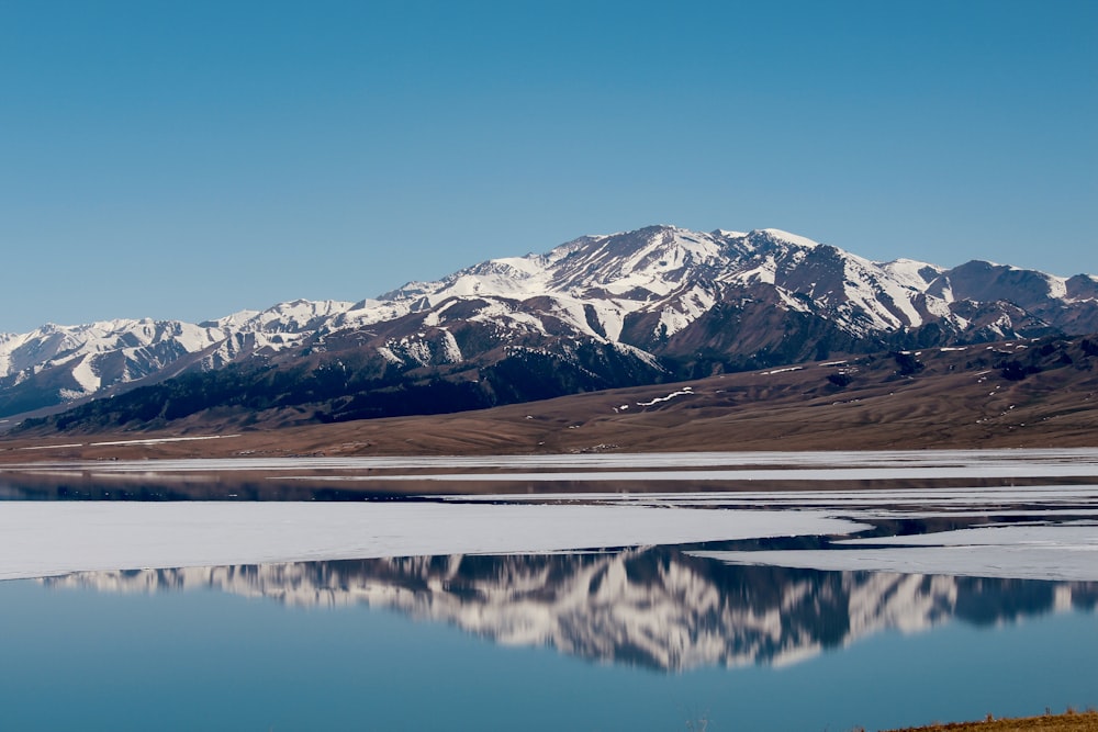 snow covered mountain near lake during daytime