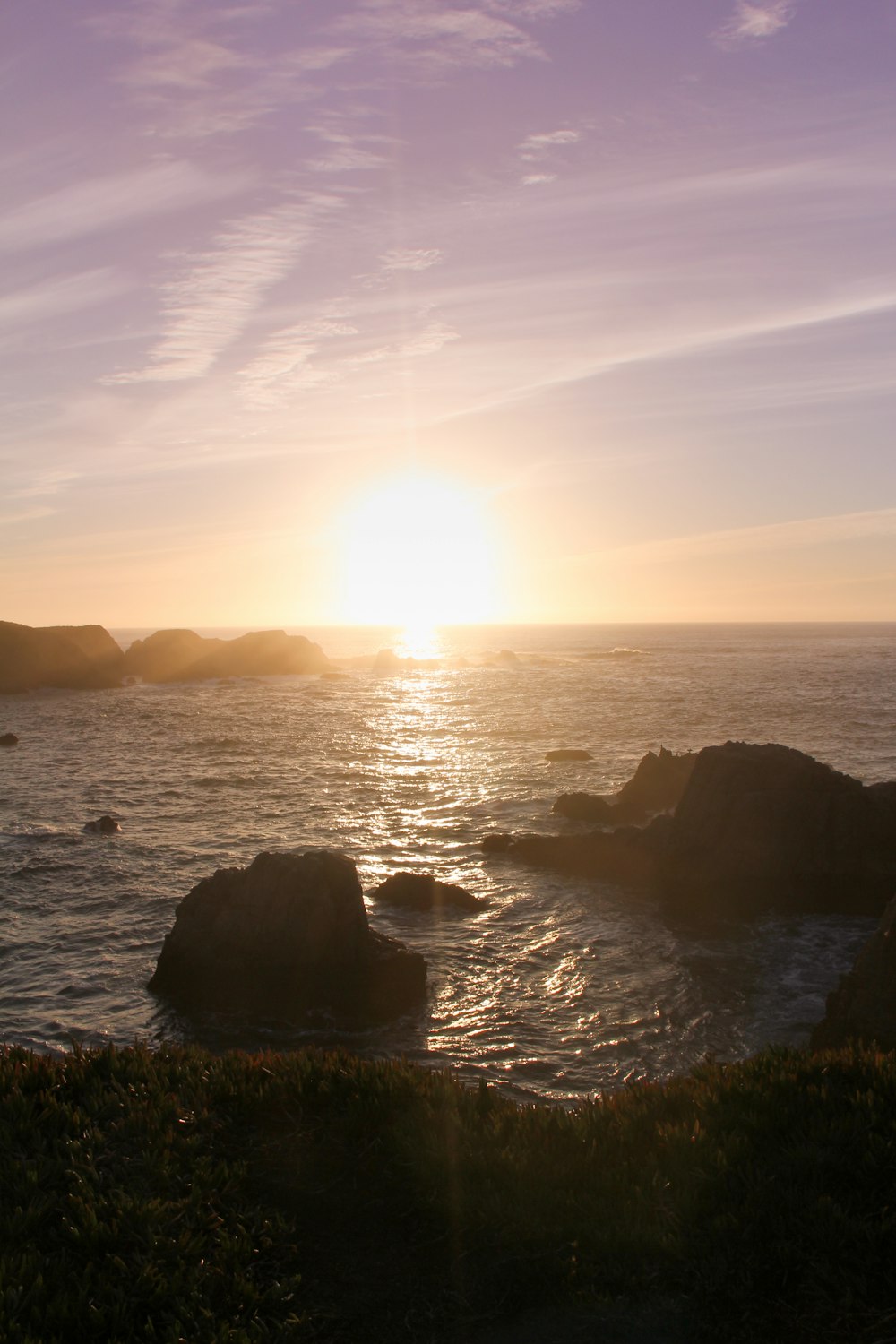 silhouette of rock formation on sea during sunset