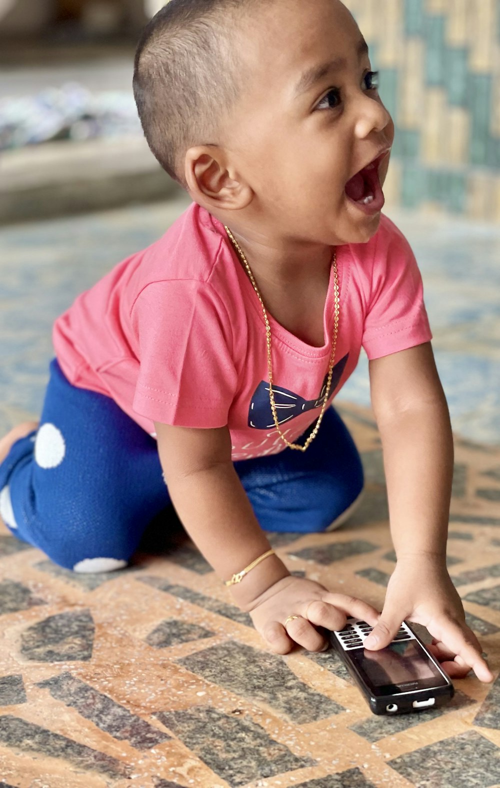 girl in pink shirt and blue pants sitting on floor