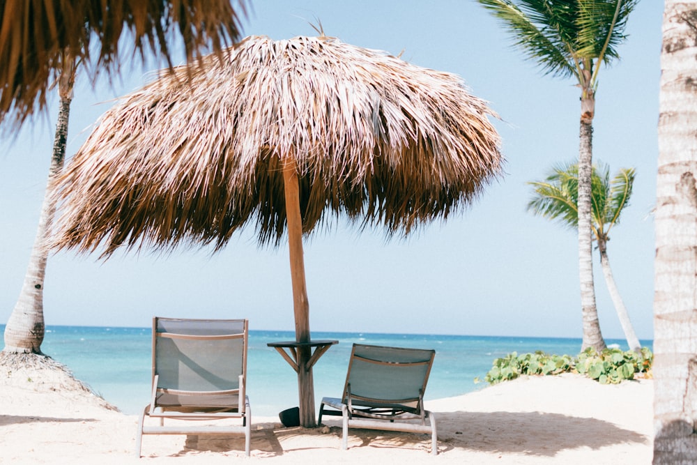 brown beach umbrella near white lounge chair under blue sky during daytime