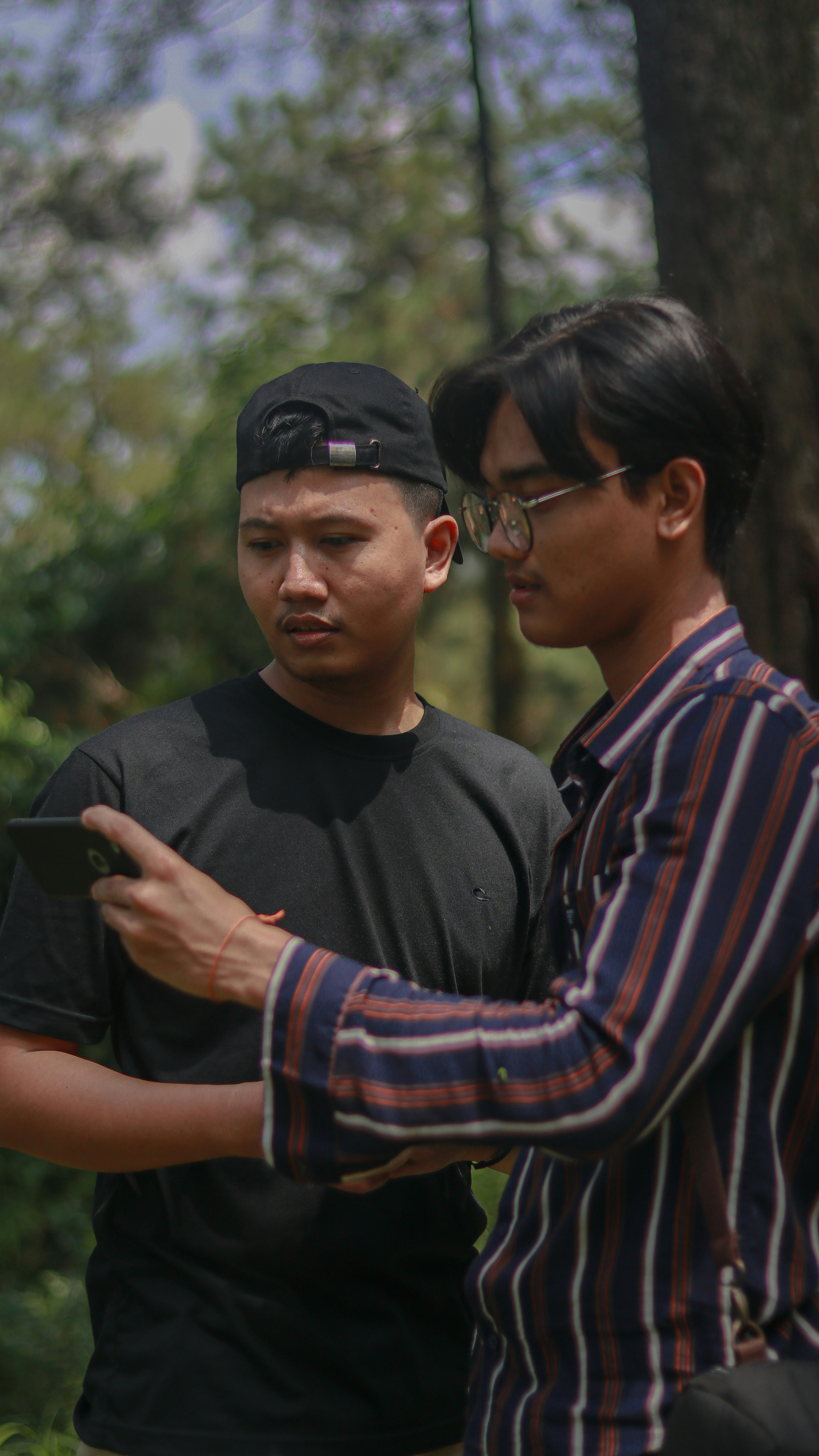 Pria dengan kemeja leher kru bergaris hitam dan putih mengenakan topi hitam