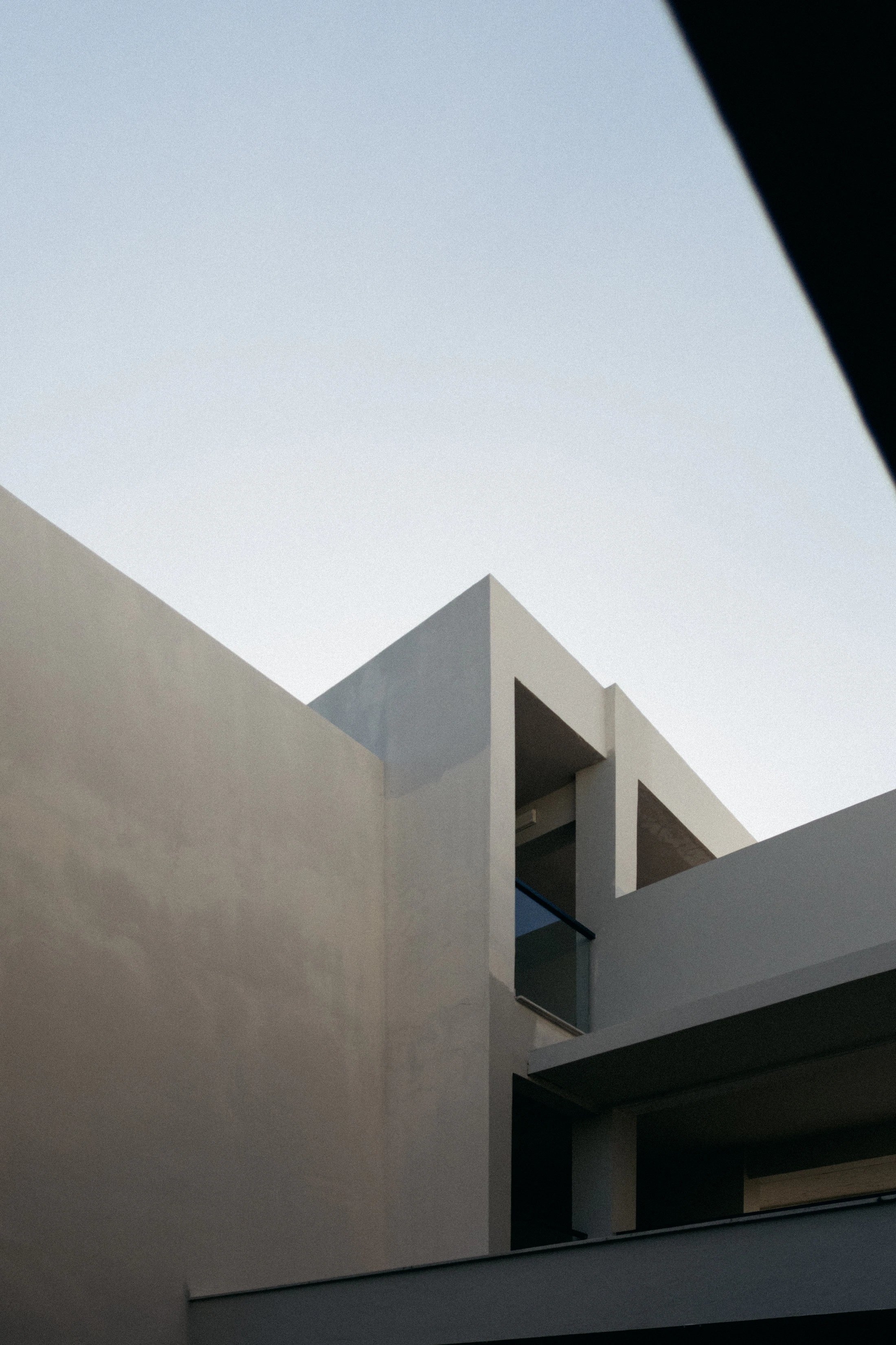 Volumes de concreto claro recortados contra o céu, com sombra marcada pela luz da tarde