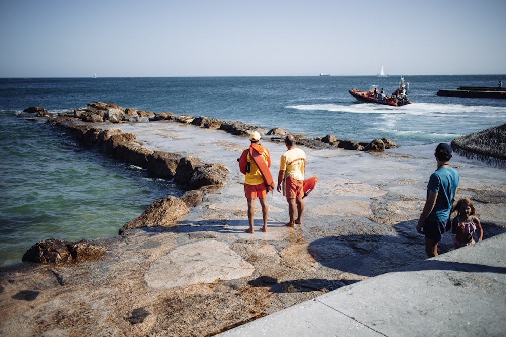 2 boys standing on gray concrete dock during daytime