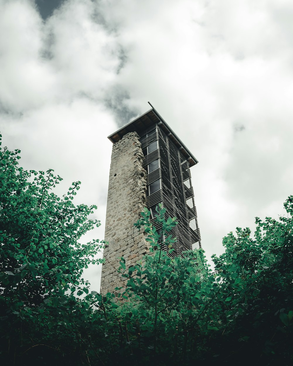 brown concrete building near green trees under white clouds during daytime