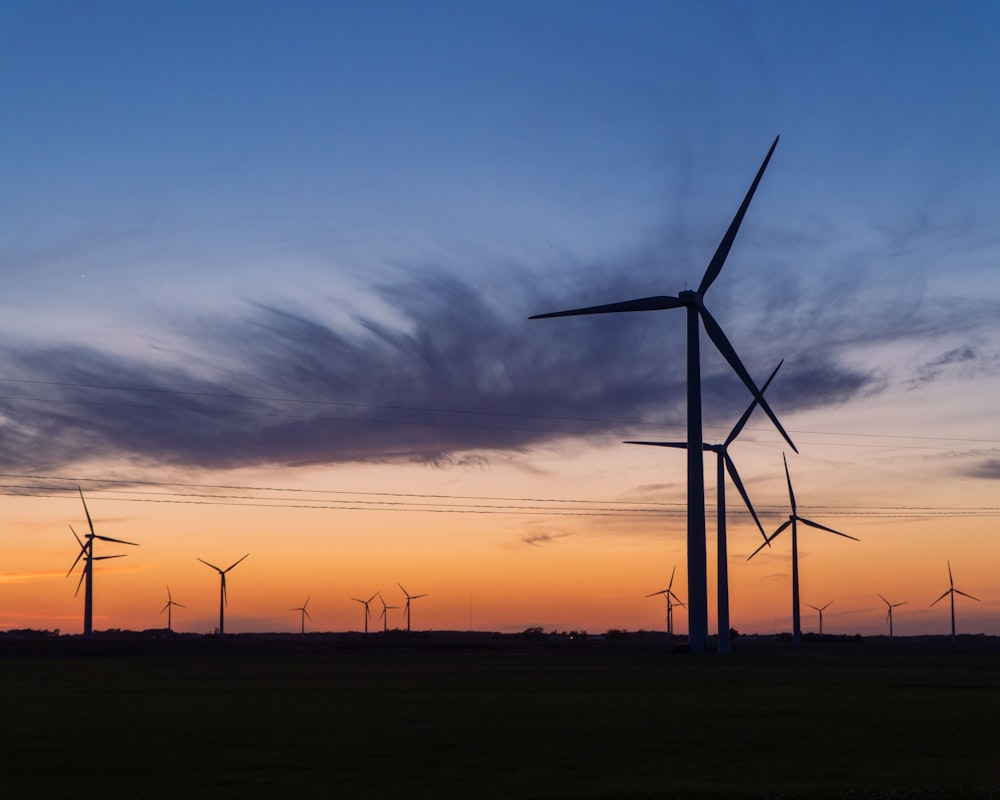 wind turbines under cloudy sky during sunset
