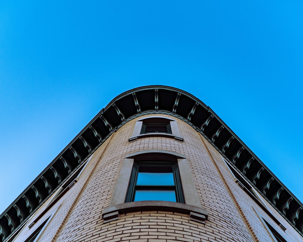 low angle photography of beige concrete building under blue sky during daytime