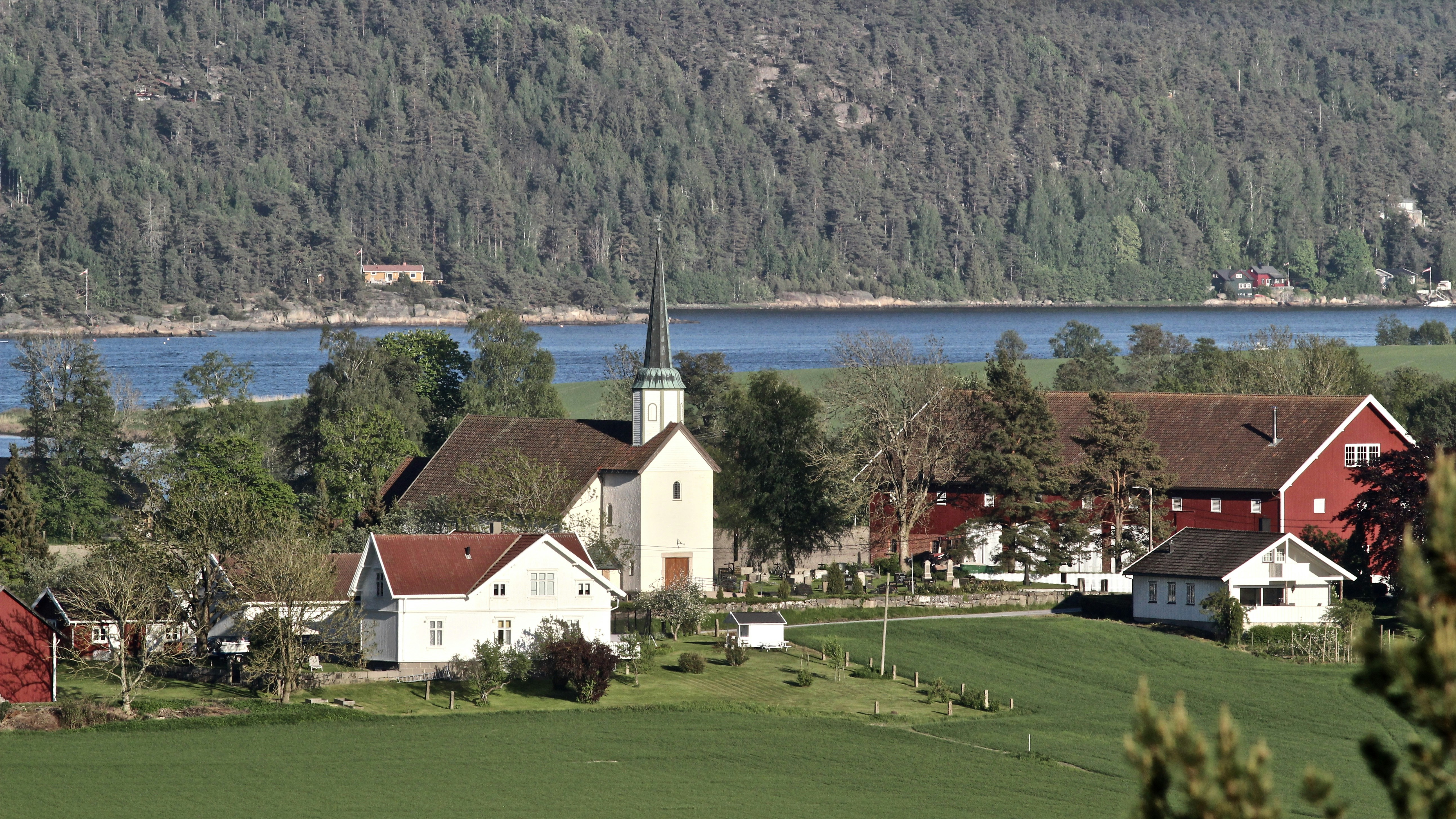 Weißes und braunes Betonhaus in der Nähe von grünem Grasfeld und Bäumen tagsüber