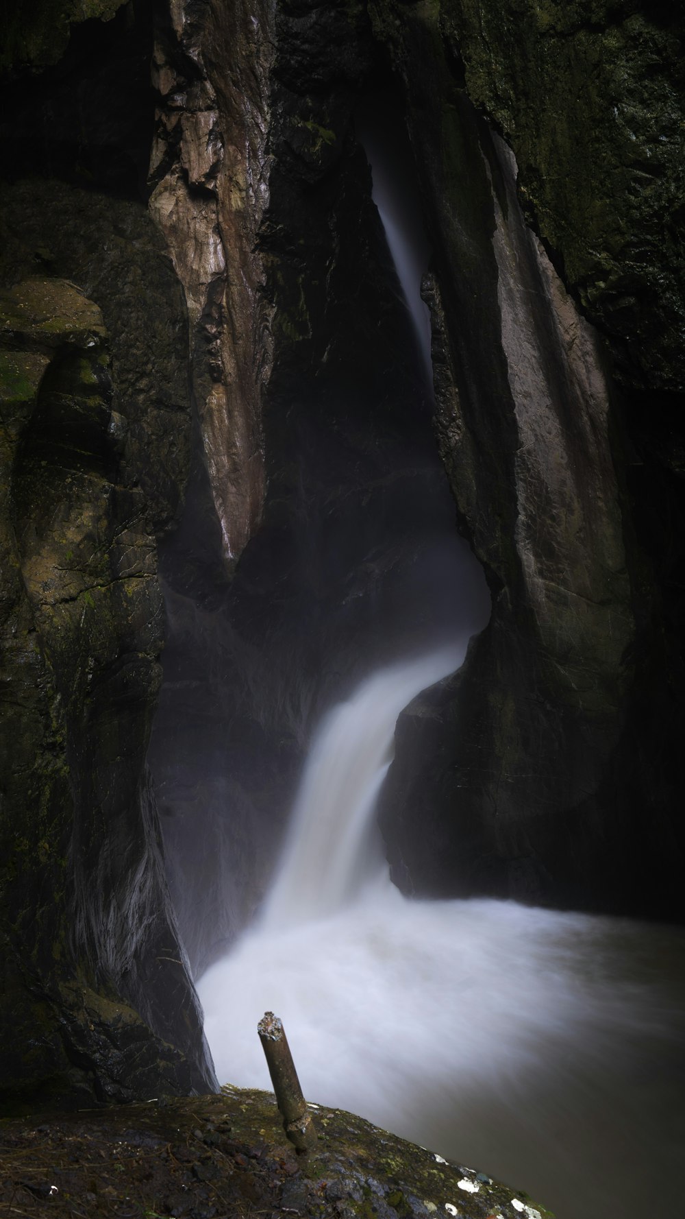 water falls between brown and green rock formation during daytime
