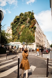 woman in brown jacket standing on sidewalk during daytime