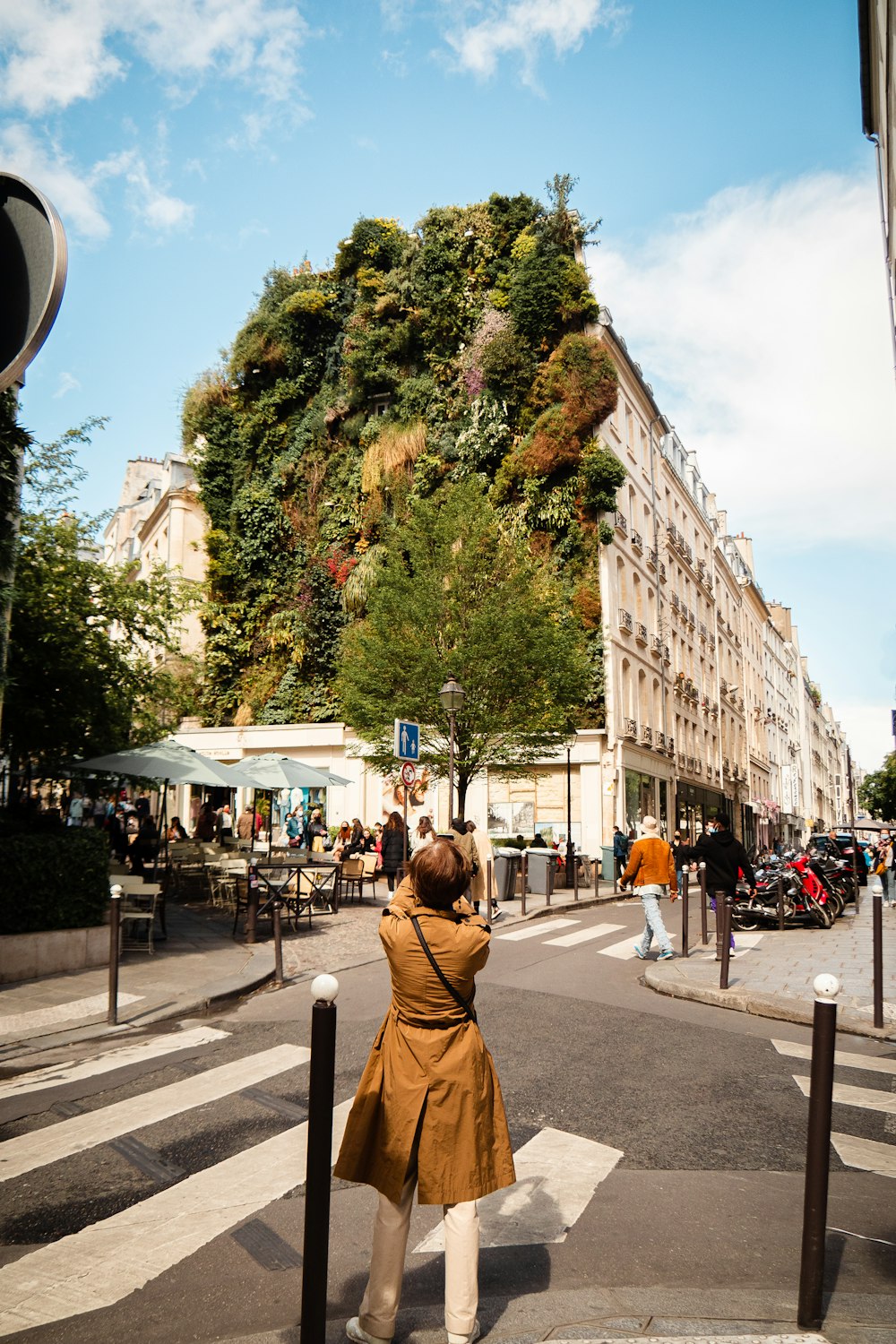 woman in brown jacket standing on sidewalk during daytime