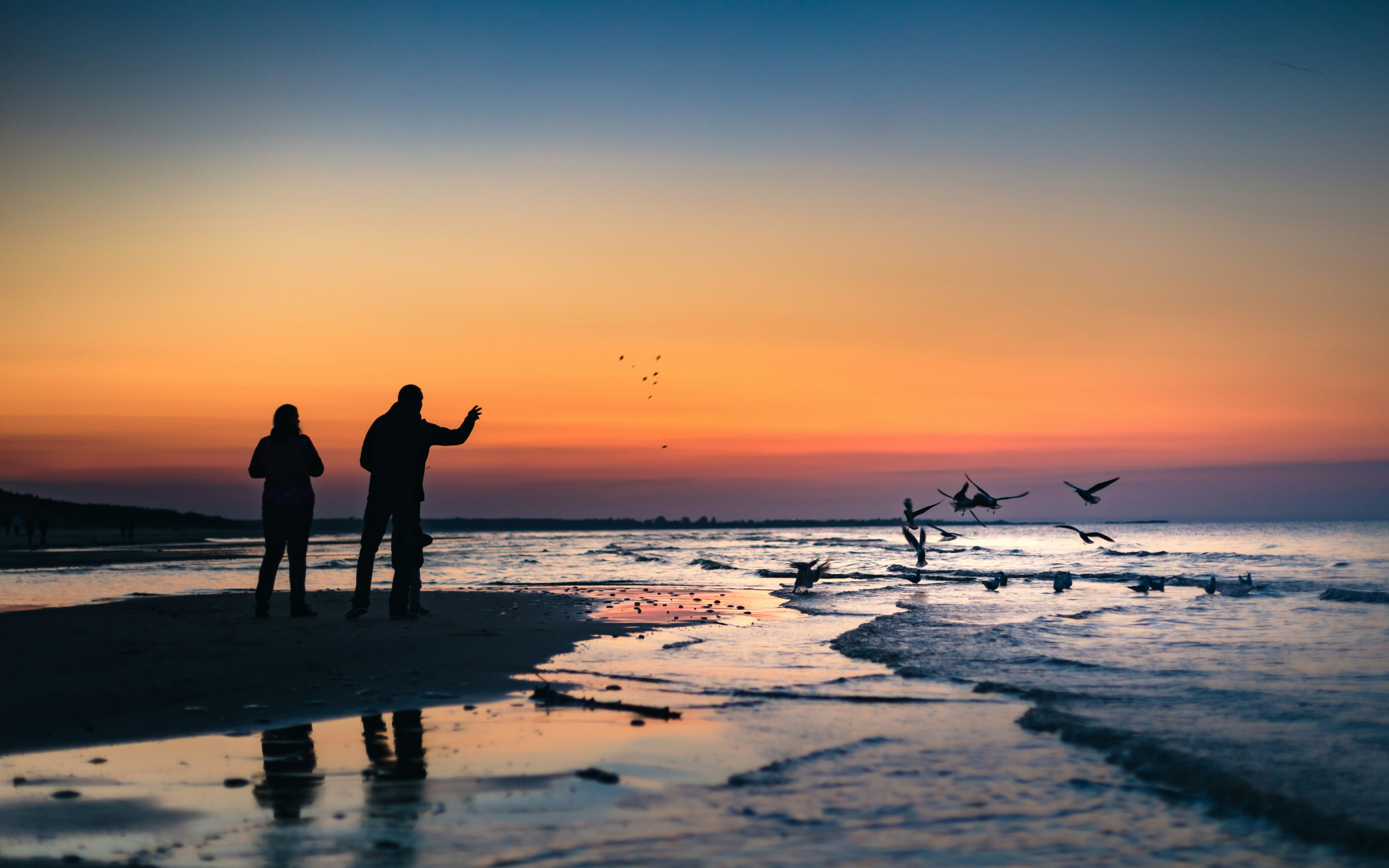 Two People Walking On The Beach In The Sunset