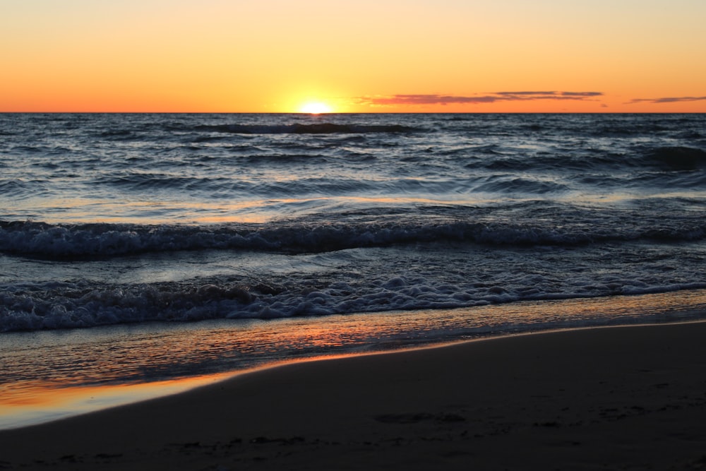 sea waves crashing on shore during sunset