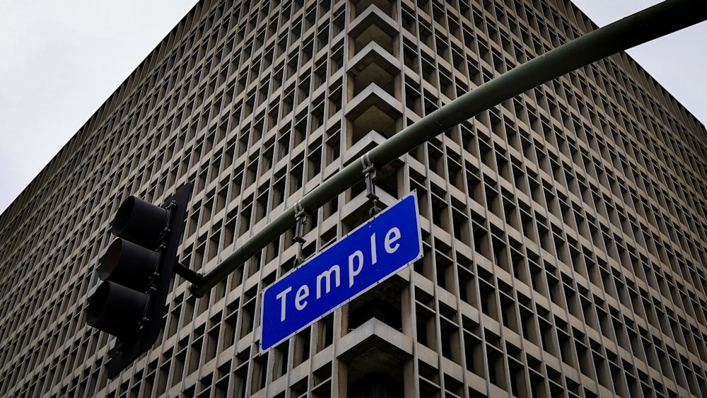 a blue street sign hanging from the side of a traffic light