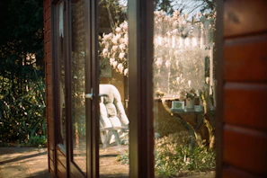 A glass-paneled door reflecting a sunny outdoor garden scene.