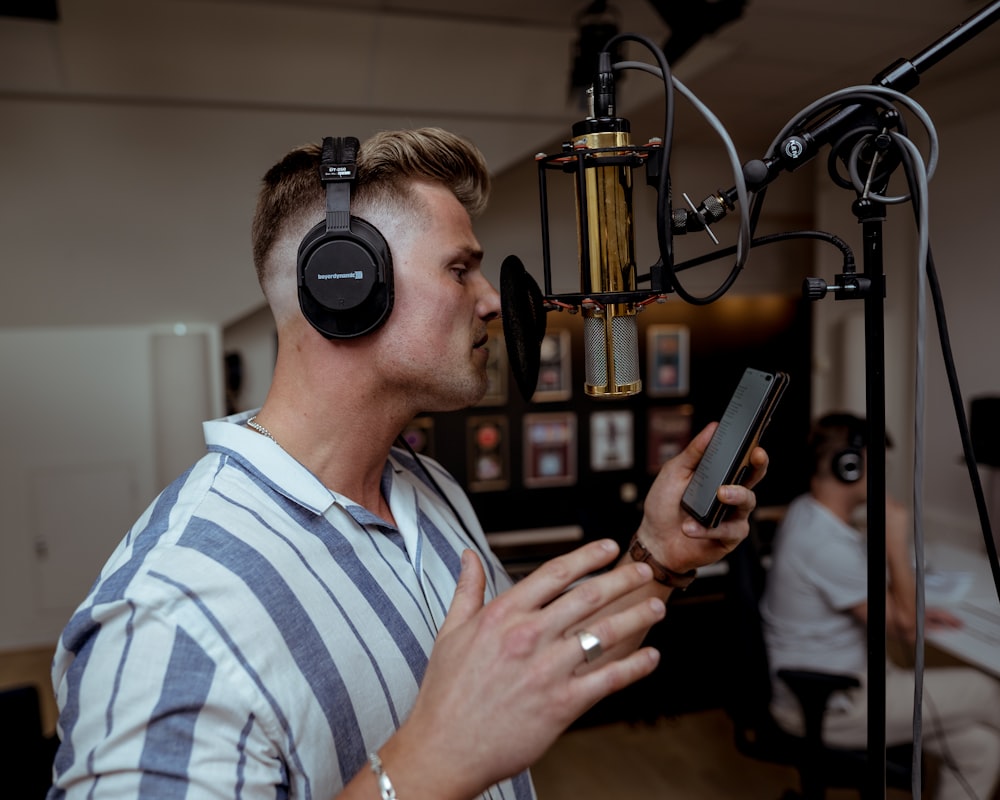 man in blue and white striped polo shirt holding black smartphone