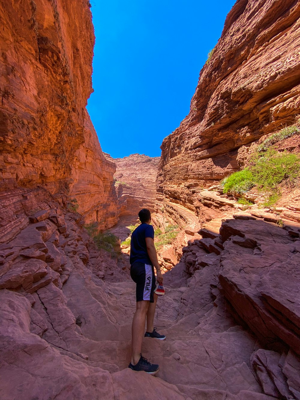 man in black jacket and blue denim shorts standing on rocky mountain during daytime