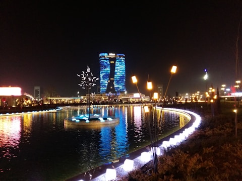 A sleek, neon royal blue flood barrier system installed along a city riverbank at dusk.